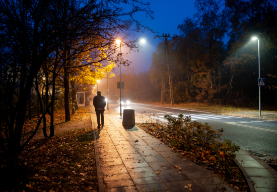 Mężczyzna spacerujący nocą chodnikiem