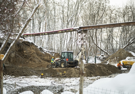 Robotnicy i maszyny pracują przy budowie wiaduktu w zimowy dzień