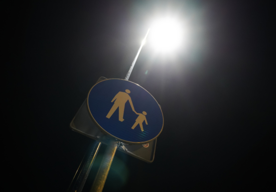 Znak drogowy oświetlony lampą uliczną.