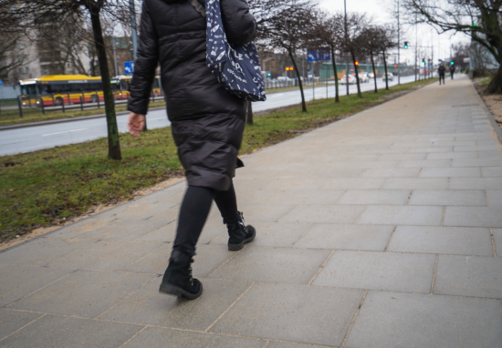 Kobieta spacerująca chodnikiem.