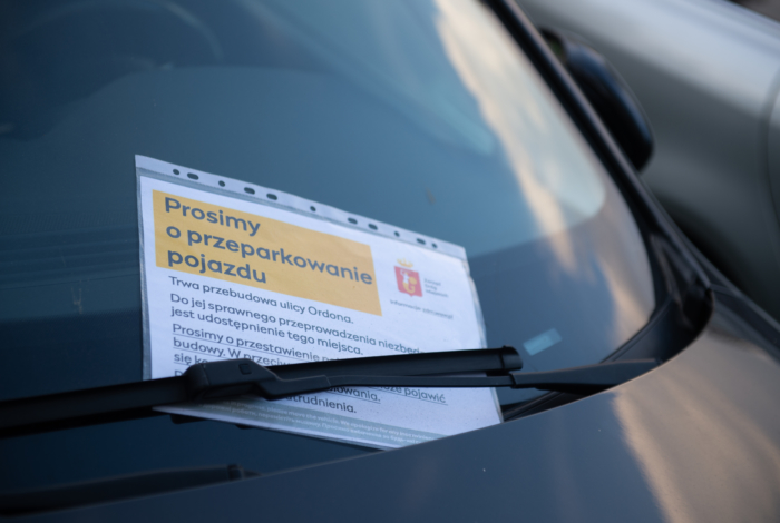 Kartka z informacjami pozostawiona za wycieraczką samochodu.