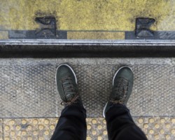 Buty fotografa na krawędzi chodnika przed wejściem do autobusu.