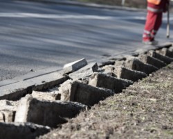 Doły przy krawędzi ulicy Rembielińskiej po usuniętych zniszczonych krawężnikach.