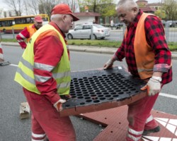 Robotnicy montują progi zwalniające progi na ulicy Umińskiego.