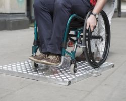 Pracownik ZDM na wózku inwalidzkim przejeżdża uskok.
