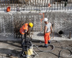 Dwóch robotników wstawia zbrojenia pod beton,