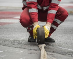 Robotnik rozwija przewód wodny.