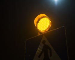 Znak drogowy informujący o przejściu dla pieszych nocą.