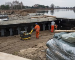 Robotnicy utwardzają ziemię podczas budowy przepustu.