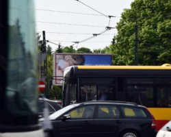 Reklama wielkoformatowa za przejeżdzającym autobusem.