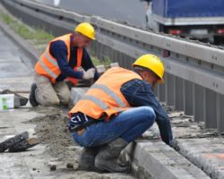 Robotnicy remontują krawężniki wiaduktu.