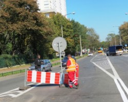 Robotnicy usuwają tymczasowy znak drogowy.