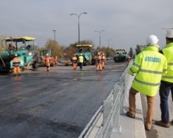 Kierownicy budowy obserwują postęp prac przy układaniu nawierzchni.