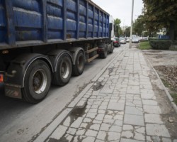 Ciężąrówka przejeżdza ulicą Ordona obok starego zniszczonego chodnika.