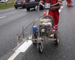 Mężczyzna malujący specjalnym sprzętem linie buspasa.