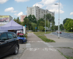 Na zdjęciu widać drogę rowerową. chodnik, jezdnię, samochody i budynki