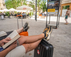Podróżnicy czytają książki z założonymi na walizkach nogami na placu Pięciu Rogów