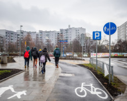 Na zdjęciu widać idących chodnikiem uczniów, drogę rowerową i przejście dla pieszych