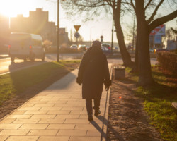 Kobieta w płaszczu idzie świeżo wyremontowanym chodnikiem na ul. Płaskowickiej w słoneczny dzień