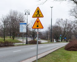 Znak sygnalizacji świetlnej i przejścia na pasach, jezdnia i tablica wskazująca dzielnice