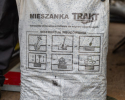 Pracownik trzyma mieszankę mineralno-asfaltową do napraw cząstkowych