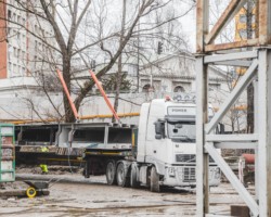 Plac budowy, a na nim samochód ciężarowy i stalowe elementy przeznaczone do montażu na filarach