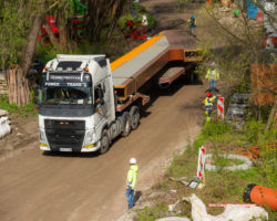 Samochód ciężarowy na terenie budowy mostu i robotnicy przy pracy