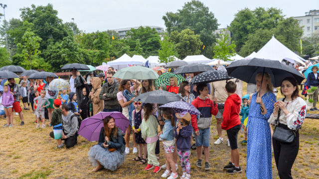 Tłumnie zgromadzeni uczestnicy kampanii Rowerowy Maj skrywają się przed deszczem pod kolorowymi parasolami