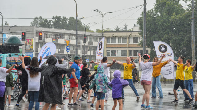Tłum ludzi radośnie tańczy w deszczu