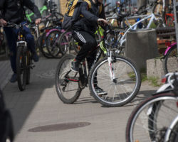 Uczeń dojeżdżający na rowerze na parking rowerowych wśród wielu innych rowerów