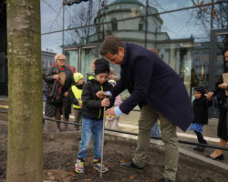 Prezydent Warszawy Rafał Trzaskowski wraz z chłopcem wbija pamiątkową tabliczkę pod nowo posadzonym drzewem na placu Trzech Krzyży
