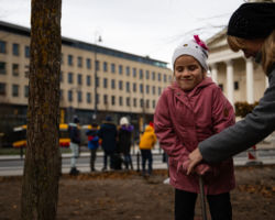 Dziewczynka wbija tabliczkę z wygrawerowanym napisem "Drzewo rośnie z dziećmi" na placu Trzech Krzyży